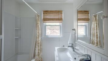Une salle de bain avec une baignoire, un lavabo et une fenêtre donnant sur un beau paysage.