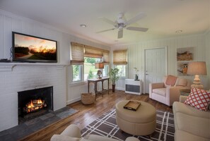 Cozy living room with a fireplace, comfortable seating, and a TV mounted on the wall.