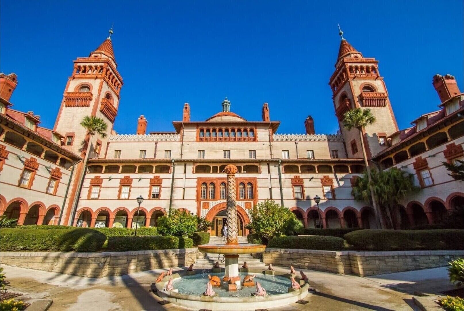 Ein großes Gebäude mit Innenhof, zwei Türmen und einem Brunnen.
