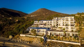 A modern multi-story hotel with a flat roof, located on a hillside with a mountain in the background. - Tranquil and Relaxing Beachfront Condo with Exceptional Views! (Los Barriles)