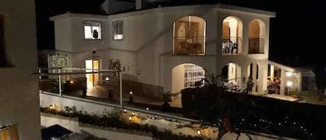Un edificio de dos pisos con un balcón, ventanas amplias y una entrada bien iluminada.