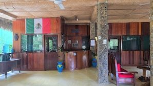 A reception area with wooden walls, a flag, a reception desk, and a water dispenser. - Hotel Nueva Alianza (Ocosingo)