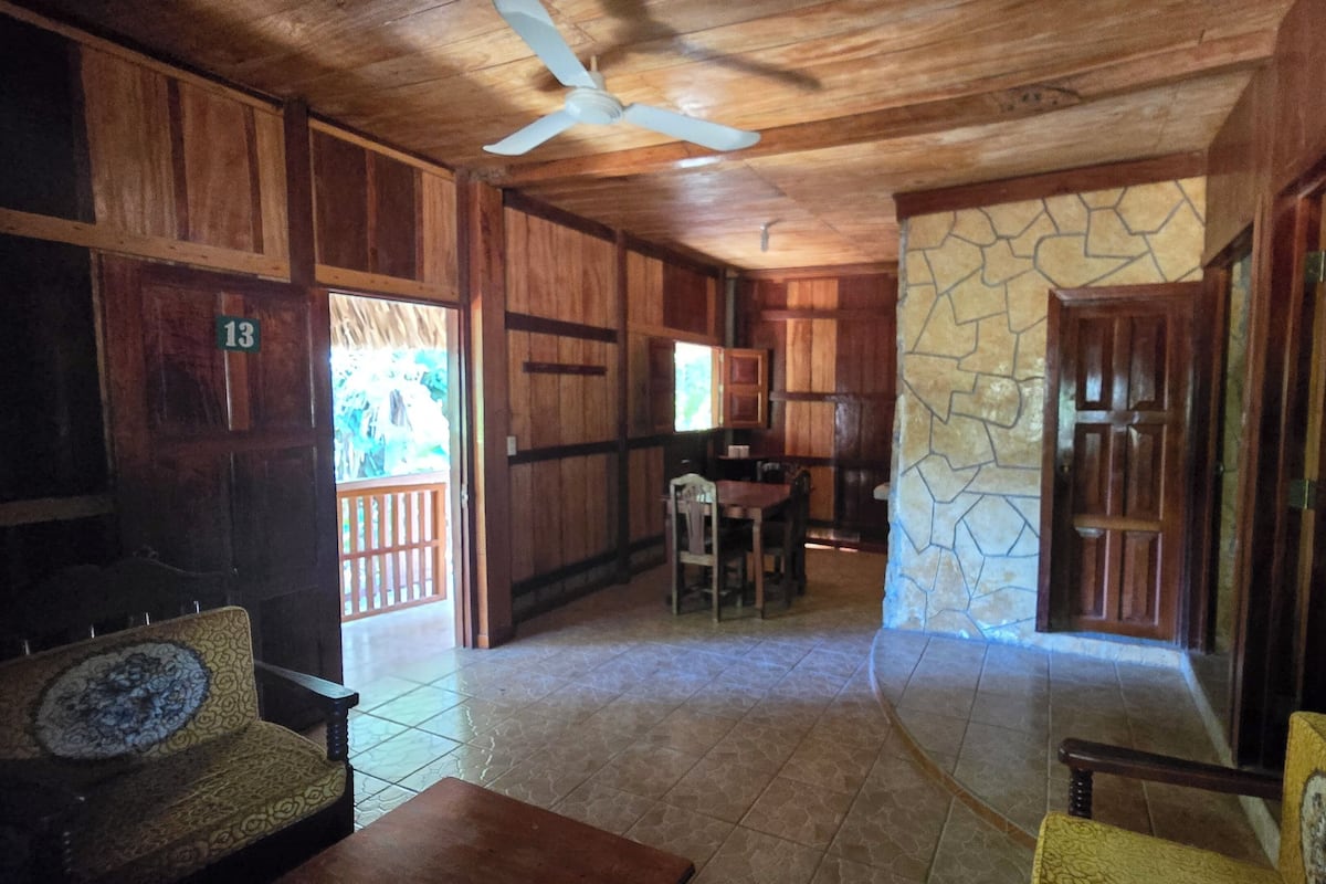 A wooden interior with a dining area, kitchen, and a stone wall.