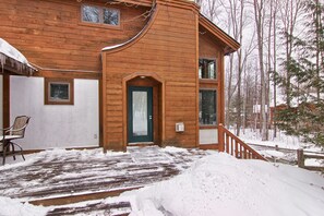 A wooden cabin with a green door, a covered porch, and a snow-covered ground. - Ski In/Ski Out on Boyneland, Slps 14 (Boyne Falls)
