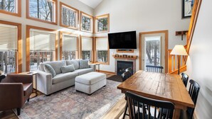 A spacious living room with a fireplace, a television, and a dining area with wooden furniture. - Ski In/Ski Out on Boyneland, Slps 14 (Boyne Falls)