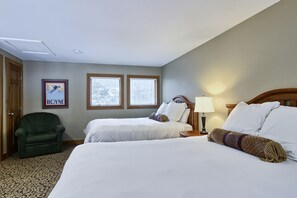 A hotel room with two beds, a green armchair, a framed picture on the wall, and two windows. - Ski In/Ski Out on Boyneland, Slps 14 (Boyne Falls)