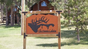 Placa para Elk Haven Cabins com silhueta de alce em um poste de madeira.