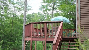 Eine Holzterrasse mit Treppe zu einer erhöhten Ebene, umgeben von üppiger Vegetation.