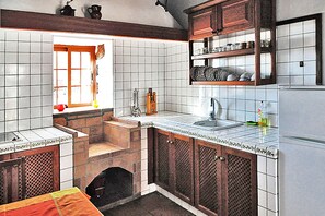 Eine Küche mit weißen Fliesen, Holzschränken, einem eingebauten Backofen und einem Fenster mit Vorhängen.