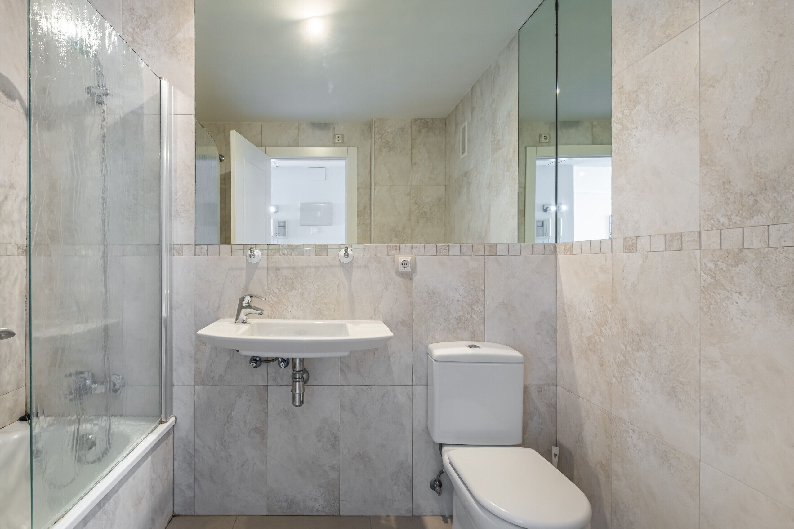 A bathroom with a glass-enclosed shower, a sink, and a toilet.