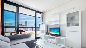 Una sala de estar moderna con un ventanal grande, un televisor de pantalla plana, un sofá y una mesa de centro de vidrio.