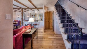 A hallway with a wooden floor, a staircase with metal railings, a dining area with a red sofa, and a kitchen with colorful tiles. - Casa Bohemia | Charming Retreat (Santa Fe)