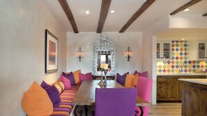 A dining area with a long table, cushioned seating, and a decorative mirror. - Casa Bohemia | Charming Retreat (Santa Fe)