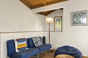 A room with a blue sofa, a floor lamp, a bean bag, and a framed picture on the wall. - Ocean's Course (Lorne)
