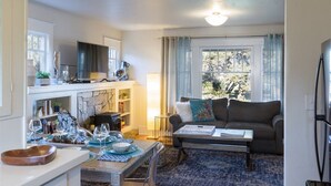 Un salon chaleureux avec une cheminée, un canapé et un coin repas où une table est dressée pour le repas.