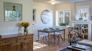 Un coin repas avec une table en bois, des chaises transparentes et un vase rempli de tournesols.