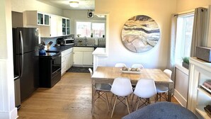 Une cuisine moderne avec un coin repas, agrémentée d’une grande œuvre d’art circulaire au mur, d’un réfrigérateur, d’une cuisinière et d’une table à manger avec des chaises.
