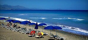 A beach with rows of sun loungers and blue umbrellas, a clear sky, and the ocean in the background. - 2 Bedrooms Modern Apartment by the SEA, Pool, Wi-Fi, A/C, Terrace, in resort (Campofelice Di Roccella)