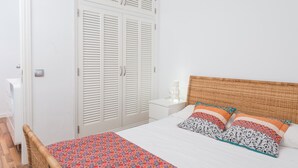 A bedroom with a bed, white wardrobe, and a wicker chair. - SUN OF ALCANADA - Apartment with sea views in Alcanada. Free WiFi (Alcúdia)