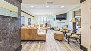 A spacious lobby with a leather sofa, armchairs, and a television.