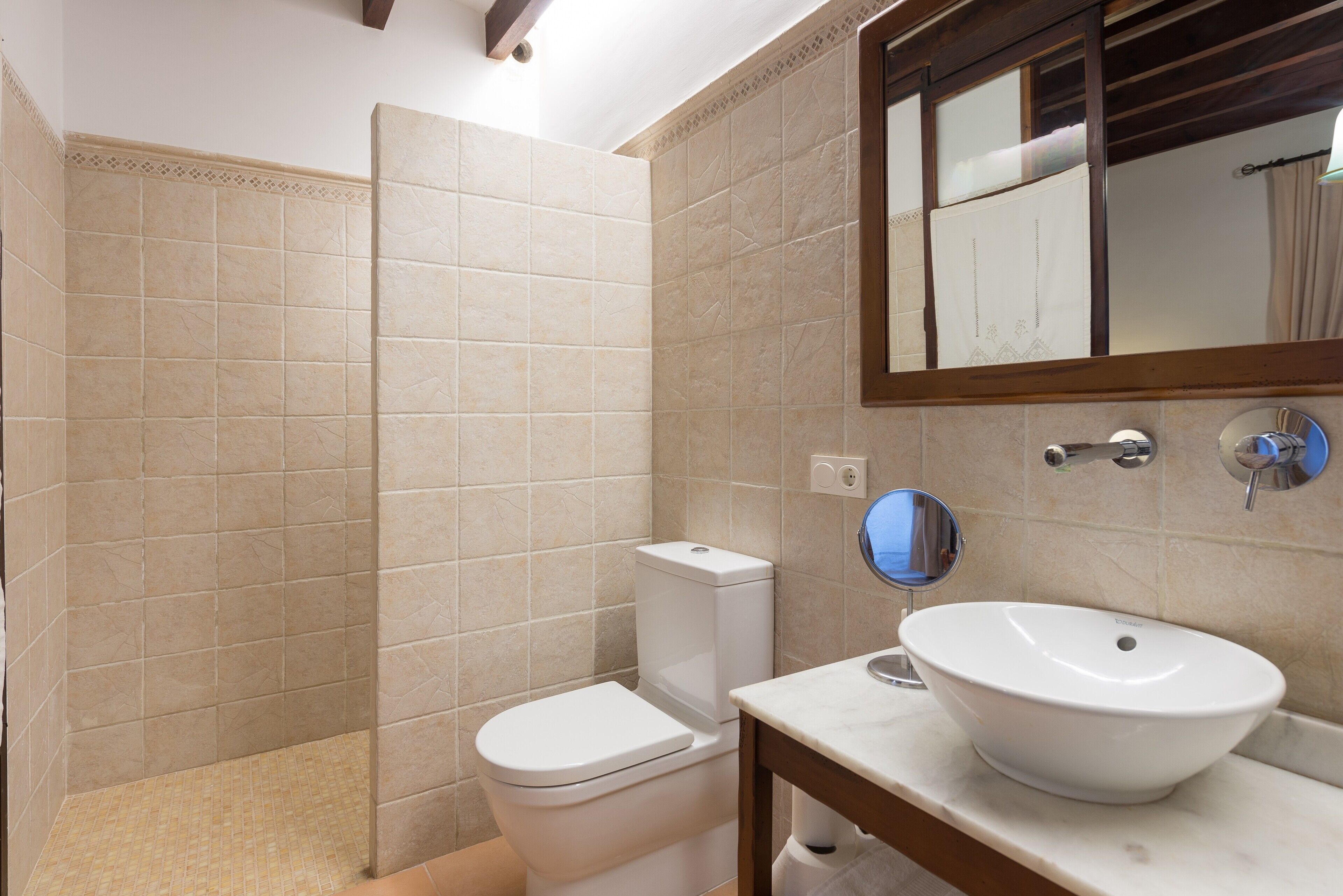 A bathroom with a toilet, sink, and mirror.