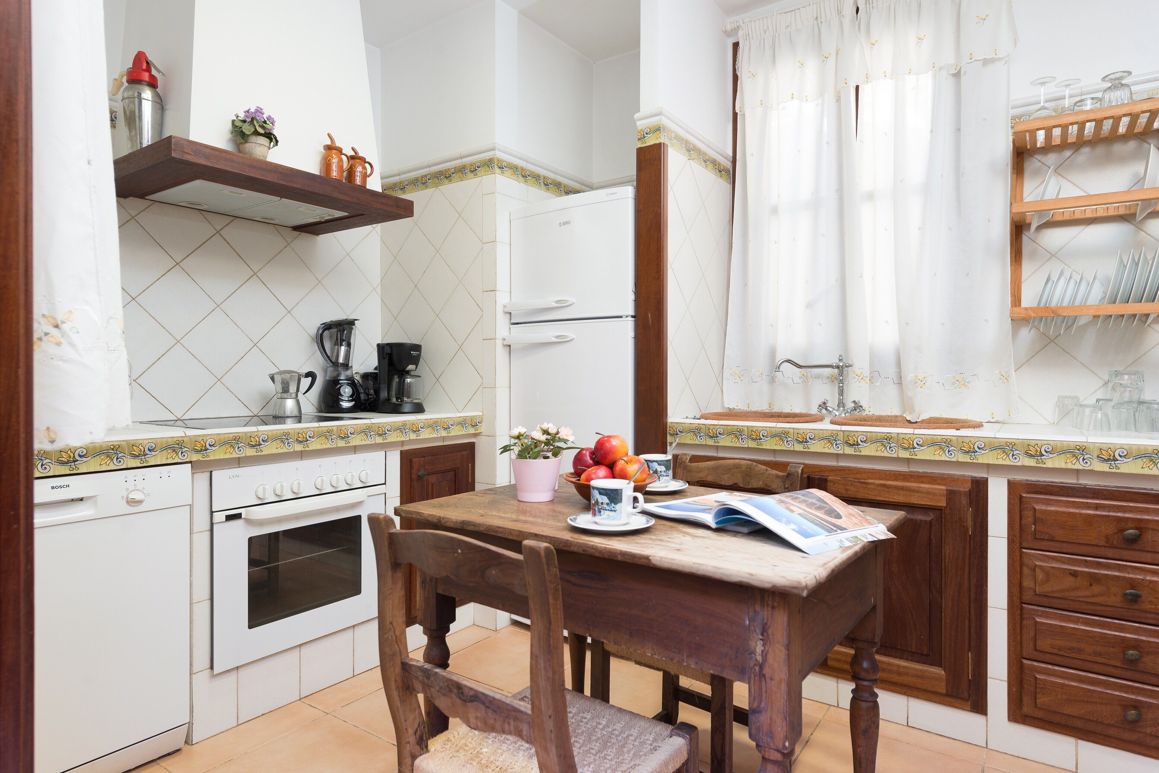 A compact kitchen with a Bosch dishwasher, a coffee maker, and a refrigerator.