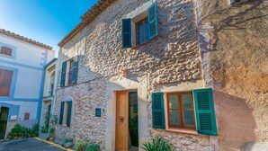 A stone building with a wooden door and green shutters, surrounded by potted plants and a clear sky. - CAN VALLORI - Nice house with interior terrace in Sencelles. Free WiFi (Sencelles)