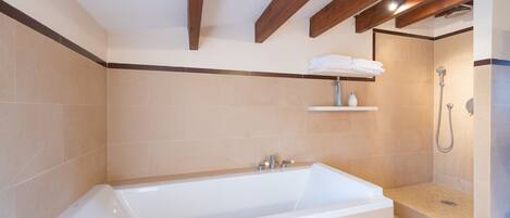 A modern bathroom with a bathtub, shower, and tiled walls.