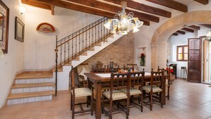 A dining area with a wooden staircase, a chandelier, and a stone wall. - CAN VALLORI - Nice house with interior terrace in Sencelles. Free WiFi (Sencelles)