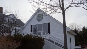 A small, single-story house with a white exterior, a central circular window, and a staircase leading to the front door. - Oceanfront Carriage House Apt. w/ Spectacular Views (York)