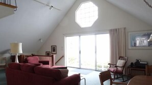 A spacious living room with a sloped ceiling, a large window, and a view of the outdoors. - Oceanfront Carriage House Apt. w/ Spectacular Views (York)