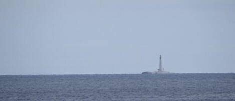Ein Leuchtturm auf einer kleinen Insel inmitten ruhiger See.