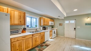 A kitchen with wooden cabinets, a microwave, a sink, and a dishwasher. There is a window with plants on the windowsill and a door with a sign on the wall. - Starstorm Mountain Apartment
Lakeview deck & hiking trail, near many activities. (Lake Junaluska)