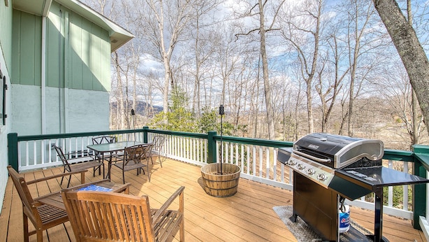A wooden deck with a grill, chairs, and a table, overlooking a forested area. - Starstorm Mountain Apartment
Lakeview deck & hiking trail, near many activities. (Lake Junaluska)