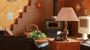 Een gezellige woonkamer met een open haard, een houten tafel met een lamp en een leren bank.