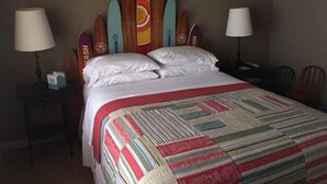 A hotel room with a bed, two bedside lamps, a chair, and a surfboard wall art. - Patterson Place is cozy and has Beautiful Waterfront (McQueeney)