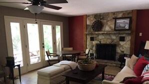 A living room with a stone fireplace, a sofa, a coffee table, and a dining area with chairs. - Patterson Place is cozy and has Beautiful Waterfront (McQueeney)