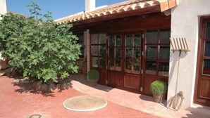 A building with a tiled roof, large windows, and a small garden area with plants and a circular mat. - Self catering Vallehermoso for 12 people (San Carlos del Valle)