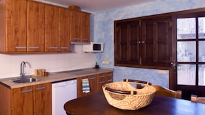 A kitchen with wooden cabinets, a microwave, a sink, and a dining table with a basket. - Self catering Vallehermoso for 12 people (San Carlos del Valle)