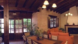A rustic interior with a brick fireplace, wooden furniture, and hanging lights. - Self catering Vallehermoso for 12 people (San Carlos del Valle)