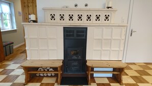 Ein Zimmer mit Kamin, zwei hölzernen Bänken, einem karierten Boden und einer Tür mit Griff.