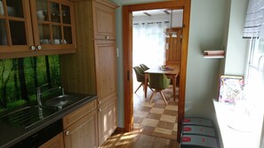 Une cuisine avec des meubles de rangement en bois, un évier et un coin repas comprenant une table et des chaises.
