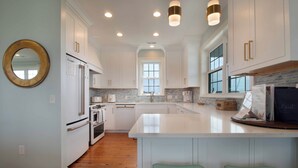 Una cocina moderna con armarios blancos, una isla central y un amplio ventanal.