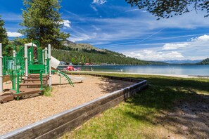 Enjoy a serene lakeside playground with a wooden deck and a beautiful lake view.