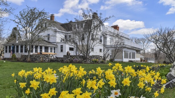 A large white house with a stone foundation, multiple windows, and a porch. - Shelter Harbor Inn (Westerly)