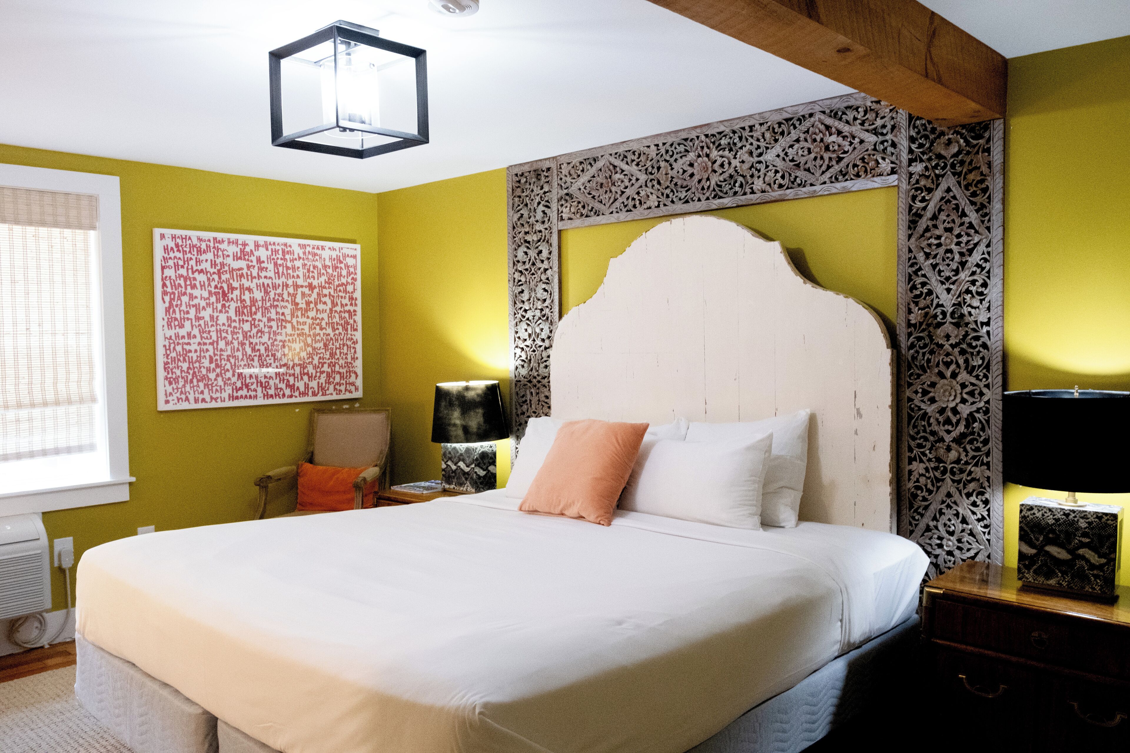 A neatly made bed with a white headboard, a bedside table with a lamp, and a decorative wall panel.