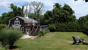 A large house with a tower, a deck, and a well-maintained lawn. - Shelter Harbor Inn (Westerly)