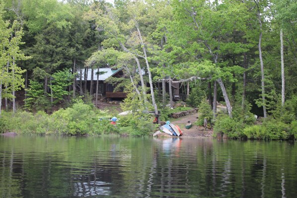 A cabin by a lake surrounded by dense forest.