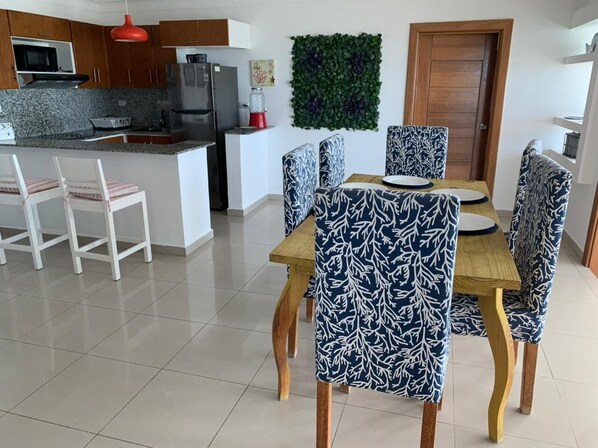 Une cuisine moderne dotée de plans de travail en granit, d’un îlot central et d’un coin repas avec des chaises à motifs et une table en bois.
