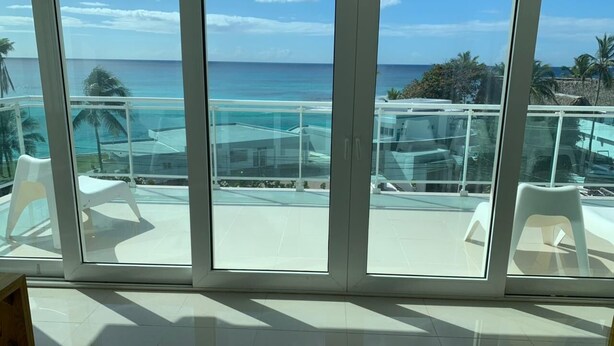 Ein Balkon mit freiem Blick auf das Meer und Palmen.